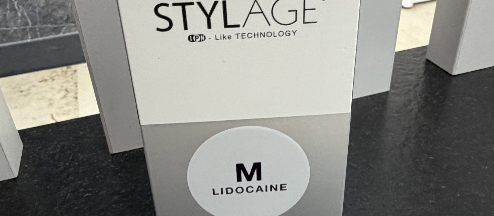 Neotevřené originální balení výplně STYLAGE M Lidocaine na pracovní desce v ordinaci